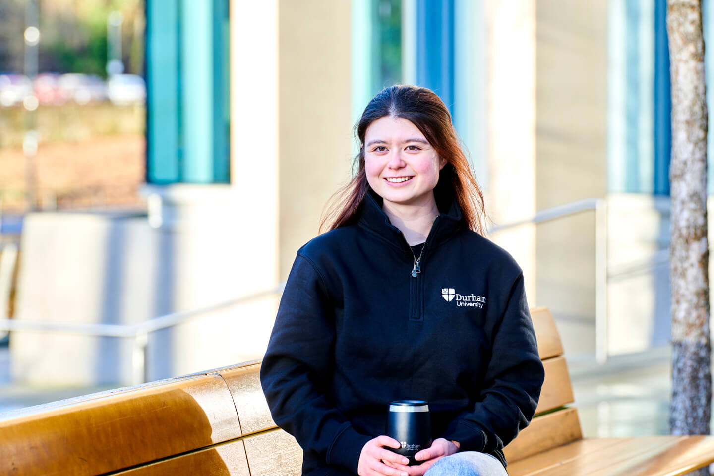Student wearing black 1/4 zip and holding SHO bottle